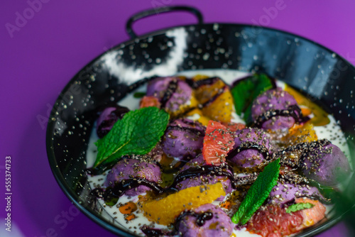 Obraz na płótnie Breakfast in black plate on purple background with lazy cheesecakes currant, strawberry, blueberry, chia, mint and coconut sauce. w salonie