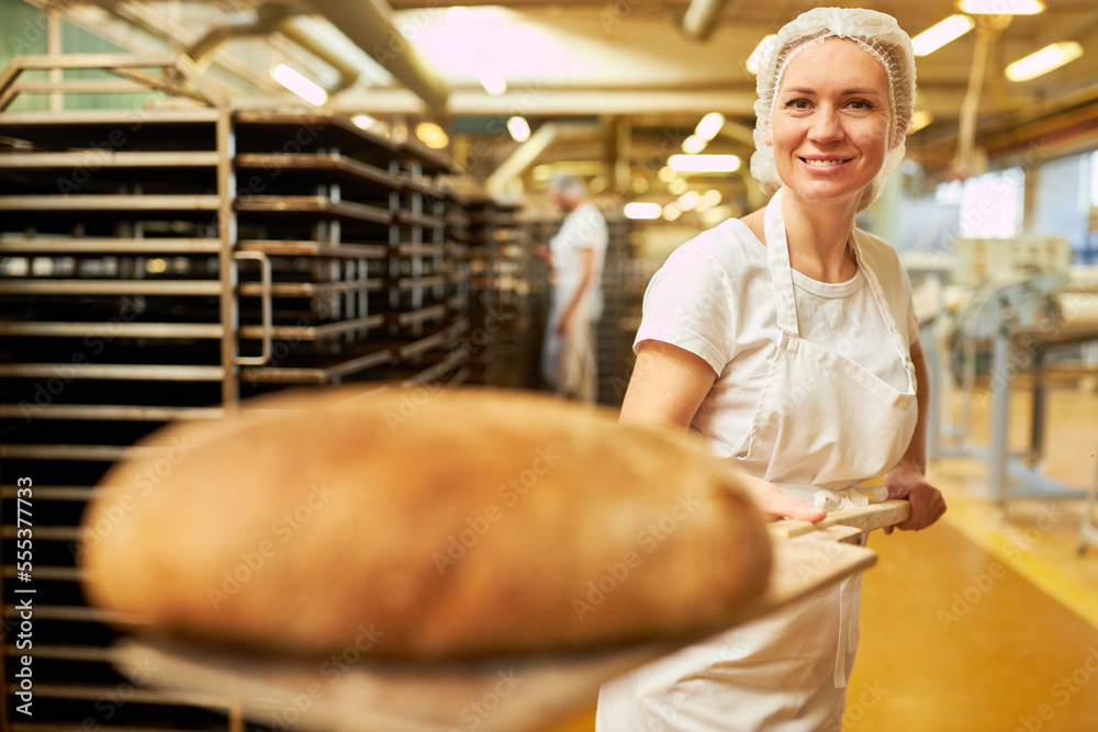 Baker apprentice holds bread scoop with ready baked bread Stock Photo