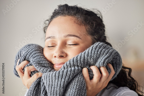 Happy, woman and fresh laundry in home with satisfied smile on face feeling clean wool sweater. Happiness, wellness and hygiene of girl cleaning in laundry room at house touching soft texture. photo