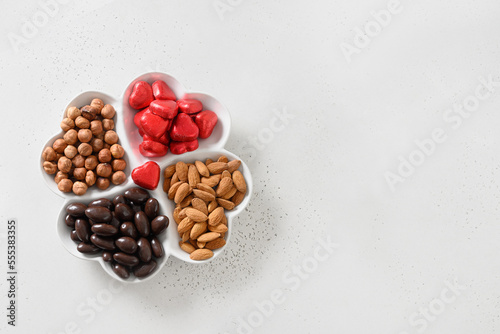 Valentine mini charcuterie board with hazelnut, almond nuts, chocolate red sweets on white background. View from above. Copy space. © svetlana_cherruty