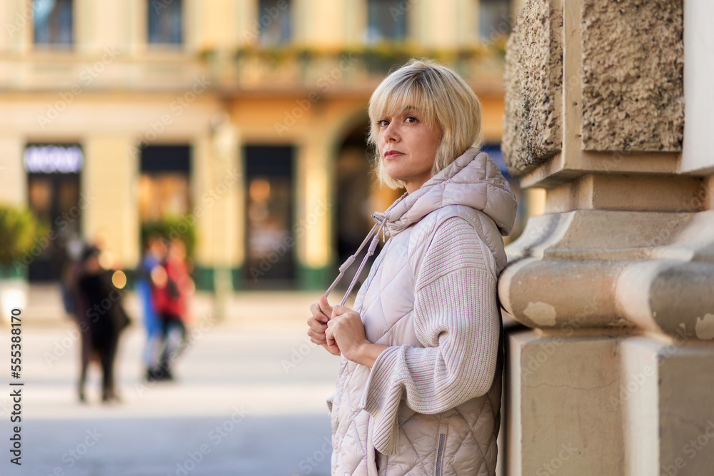 Portrait of adult alone Caucasian woman posing at column in city square. Copy space. Concept of psychology and loneliness Portrait of adult alone Caucasian woman posing at column in city square. Copy space. Concept of psychology and loneliness