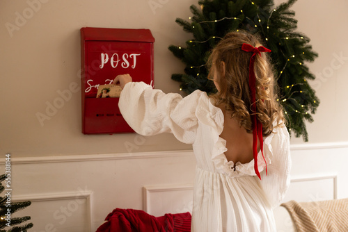 little girl send letter to Santa Claus on Christmas decorated home