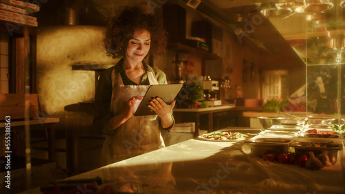 In Restaurant: Beautiful Female Chef Using Laptop Computer. Authentic Pizza Place Cooking Delicious Organic Eco Food. Bi-racial Female Entrepreneur Working on Online Order Small Business Family Shop