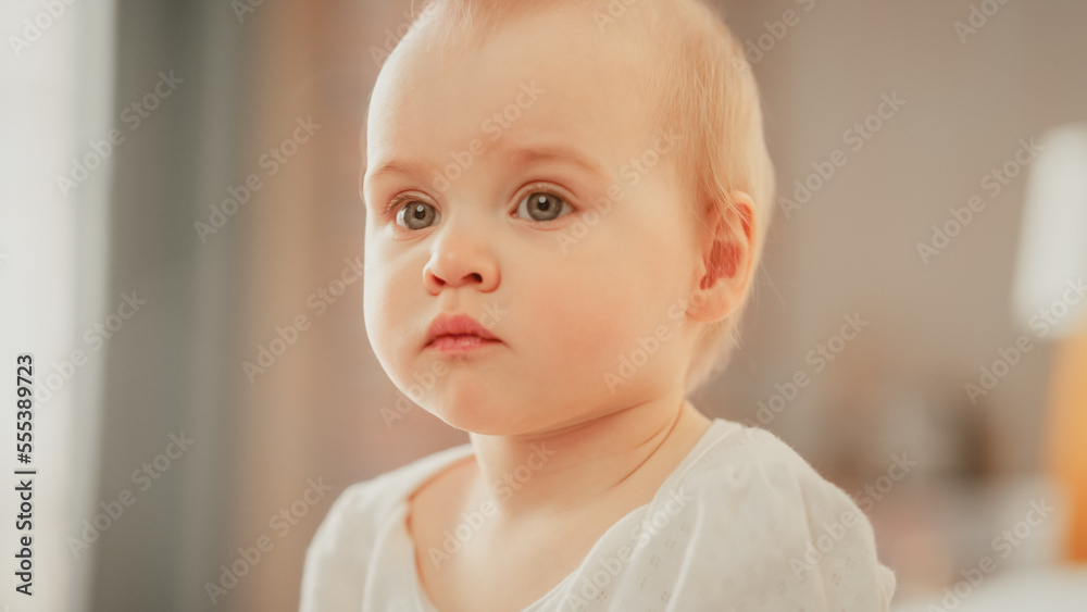 Beautiful Baby Portrait: Adorable Infant Sitting in Bed and Looking at Camera. Happy Child with Light Blond Hair at Home. Concept of Childhood, New Life, Motherhood. Beautiful Baby Portrait: Adorable Infant Sitting in Bed and Looking at Camera. Happy Child with Light Blond Hair at Home. Concept of Childhood, New Life, Motherhood.