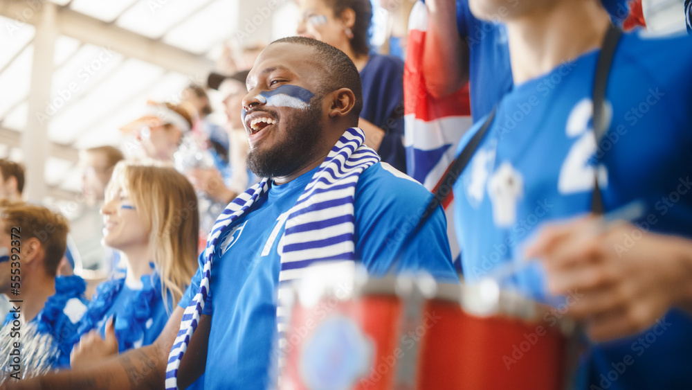 Sport Stadium Big Event: Handsome Black Man Cheering. Crowd of Fans with Painted Faces Cheer, Shout for the Blue Soccer Team to Win. People Celebrate Scoring a Goal, Championship Victory