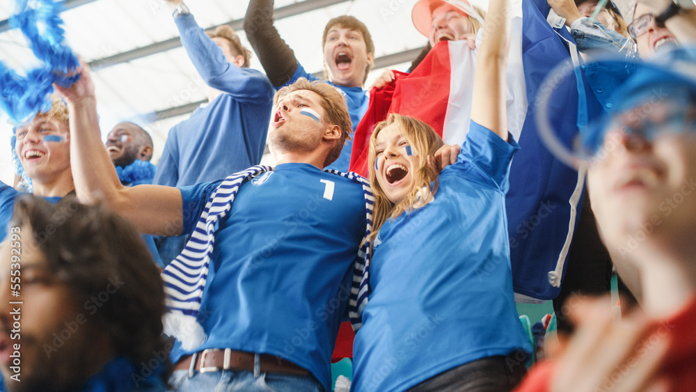 Fototapeta premium Sport Stadium Big Event: Crowd of Fans Cheer for Blue Soccer Team to Win. People Celebrate Scoring a Goal, Championship Victory. Cute Caucasian Couple with Painted Faces Cheer, Shout, Beat the Drum