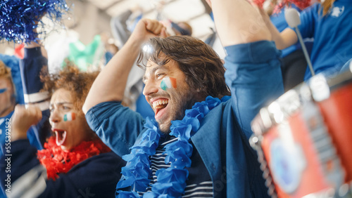 Sport Stadium Soccer Match: Portrait of Bi Racial Couple with Italian Flag Painted Faces Cheering Team to Win, Beating Tambourine. Crowd Celebrate Goal, Championship Victory