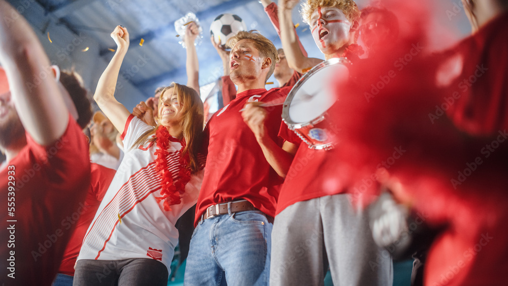 Fototapeta premium Sport Stadium Event: Crowd of Fans Cheer for Red Soccer Team to Win. People Celebrate Scoring a Goal, Championship Victory. Group of Friends with Painted Faces Have Fun. Low Angle Tribune SHot
