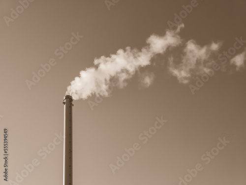 Factory chimney with smoke. Industrial pipe. Blue sky at sunny day. Air pollution. Black and white.