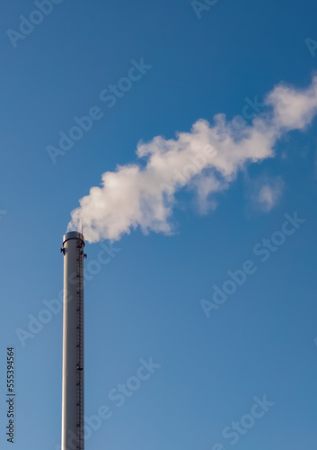 Factory chimney with smoke. Industrial pipe. Blue sky at sunny day. Air pollution/