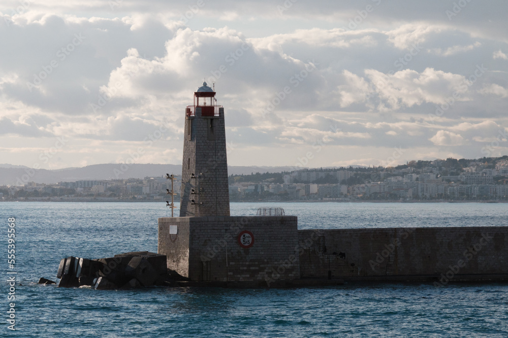 Lighthouse in the port, seascape. Beacon, sea, and clouds at sunset, Nice, France.