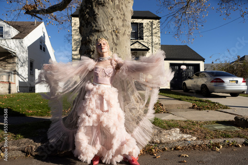 fashion portrait of non-binary person wearing pink tulle dress in suburbia