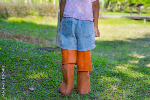 small girl wearing oversize boots prepare for gardening.