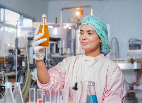 Indian female food engineer test tubes to sample beverage products in a juice beverage factory.