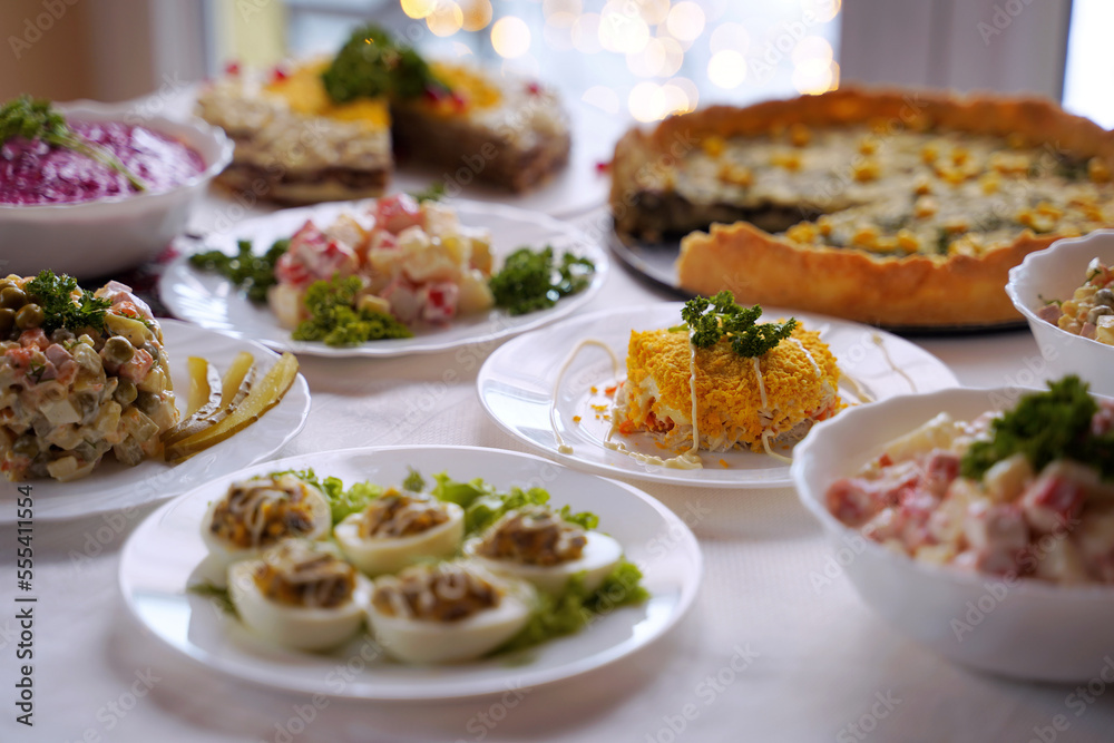 Homemade food on a festive New Year table with focus on mimosa salad.