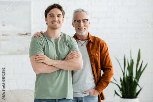 Tablou pe pânză happy mature father in eyeglasses hugging cheerful young son posing with crossed
