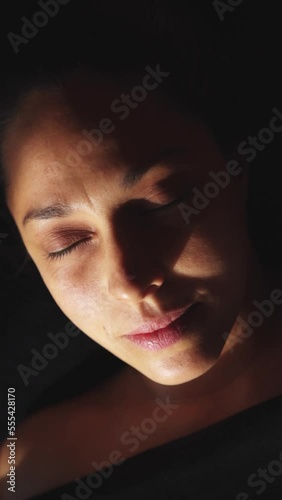 face of a woman with green eyes and sidelight opening her eyes after relaxation treatment, Shirodhara treatment, Ayurveda, vertical video, HD