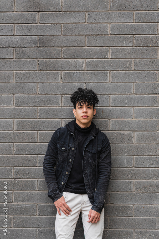 Positive Hispanic migrant guy leaning on brick wall Positive Hispanic migrant guy leaning on brick wall