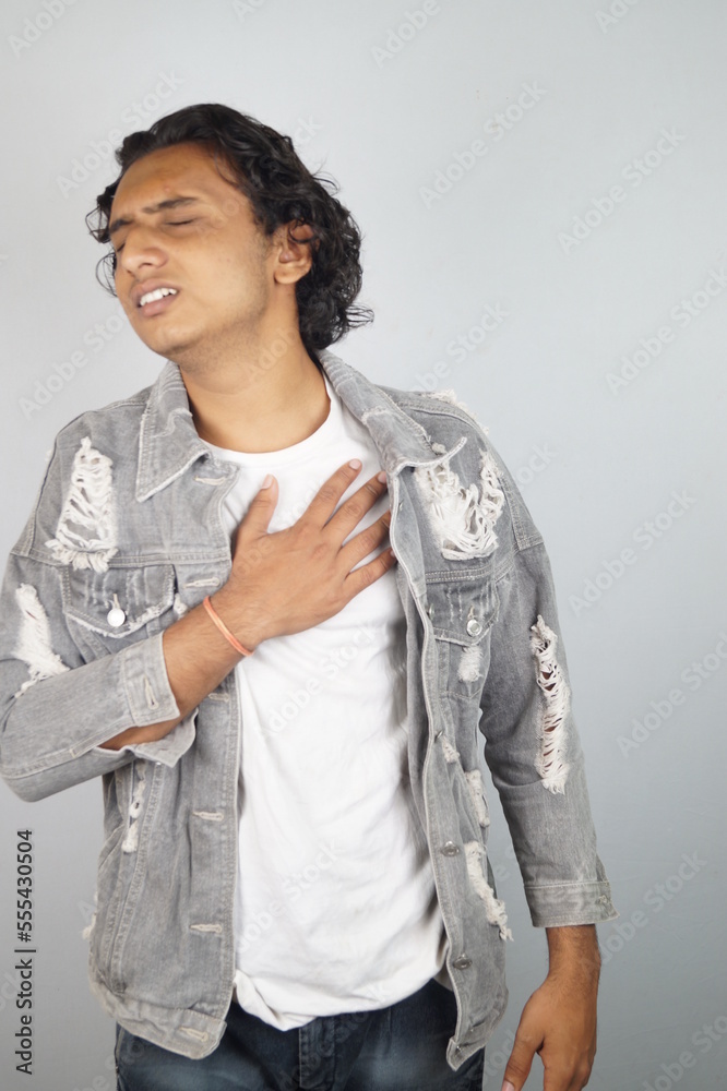 Uncomfortable man suffering chest pain while standing over white background Uncomfortable man suffering chest pain while standing over white background