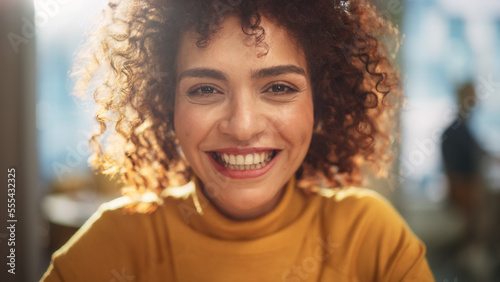 Close Up Portrait of a Beautiful Multiethnic Middle Eastern Woman with Brown Eyes and Curly Hair. Talented Young Female Smiling Charmingly, Motivating Viewer for Better Life Choices.