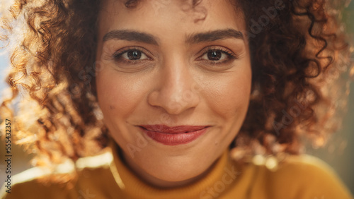 Close Up Portrait of a Young Middle Eastern Woman with Short Curly Hair, Looking for Camera, Wearing a Yellow Sweater. Beautiful Diverse Multiethnic Female Wearing Yellow Smiling and Being Happy. photo