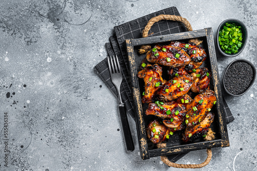 BBQ Chicken wings in Teriyaki sauce with black sesame in a tray. Gray background. Top view. Copy space