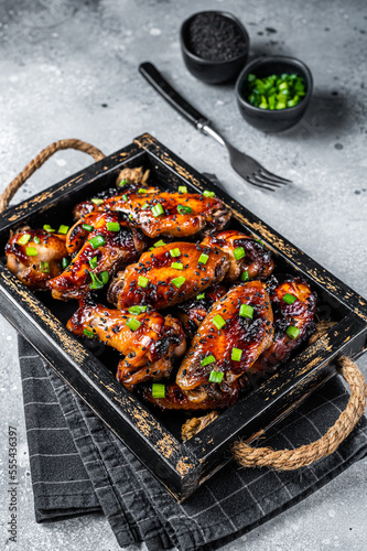 BBQ Chicken wings in Teriyaki sauce with black sesame in a tray. Gray background. Top view