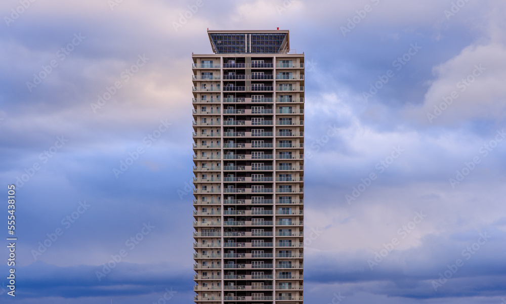 Tall residential apartment building and fluffy clouds in blue hour Tall residential apartment building and fluffy clouds in blue hour