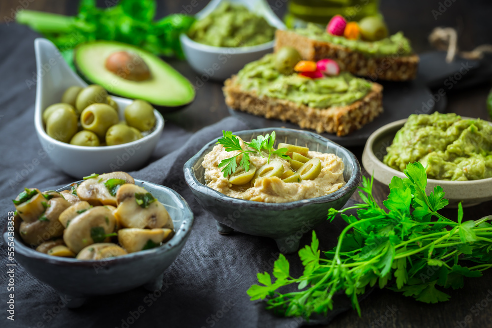 Vegan raw food snacks with fresh juicy vegetables, avocado dip and humus
