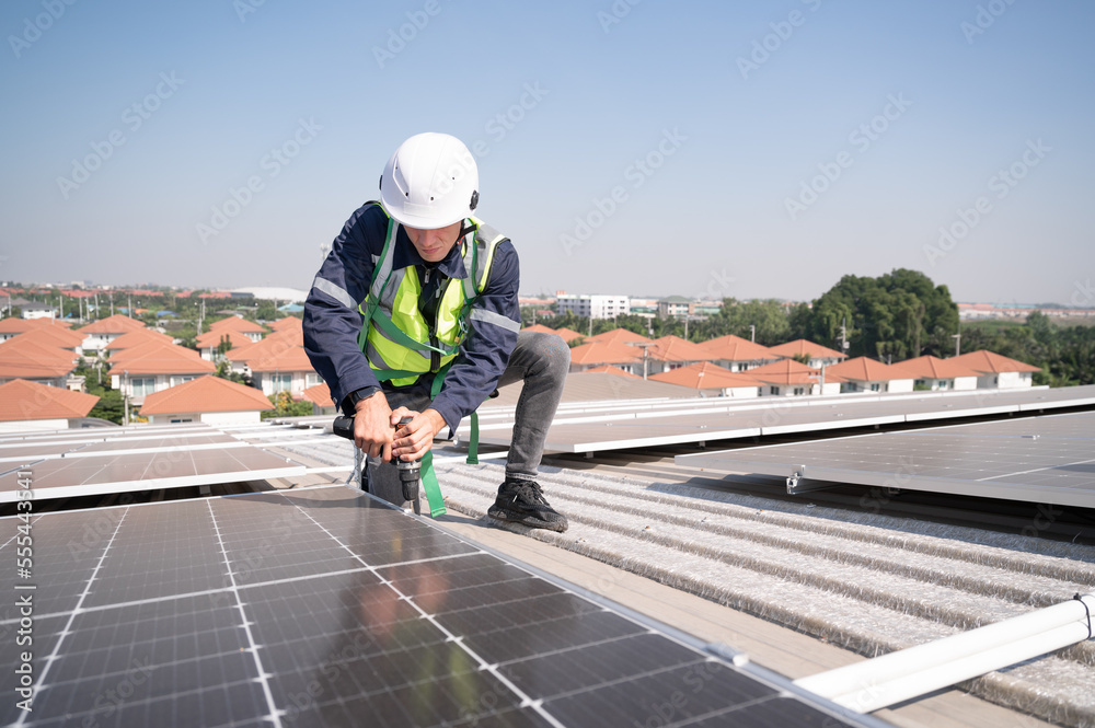 Caucasian engineer man use electric screwdriver working with solar panel on roof factory
