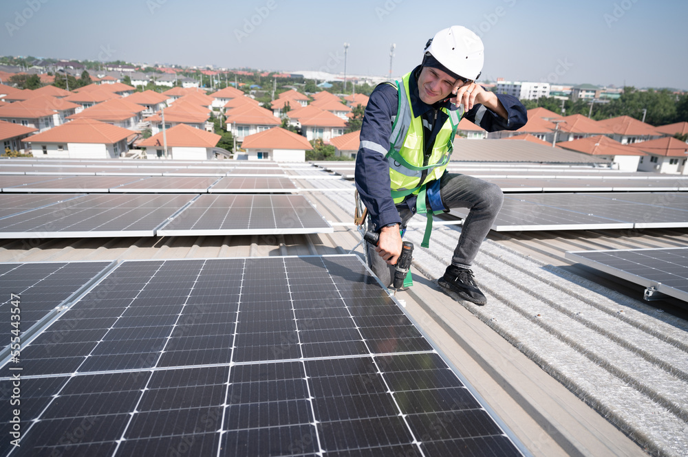 Tired Caucasian engineer man working with solar panel on roof factory Tired Caucasian engineer man working with solar panel on roof factory