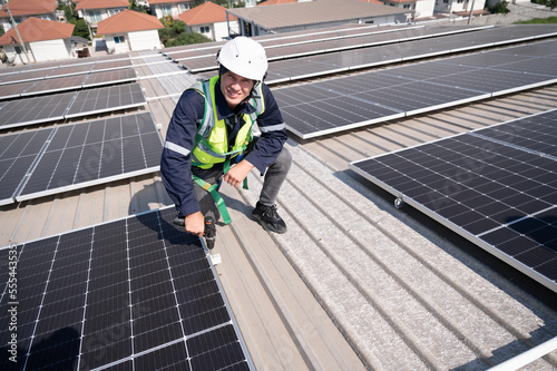 Caucasian engineer man use electric screwdriver working with solar panel on roof factory