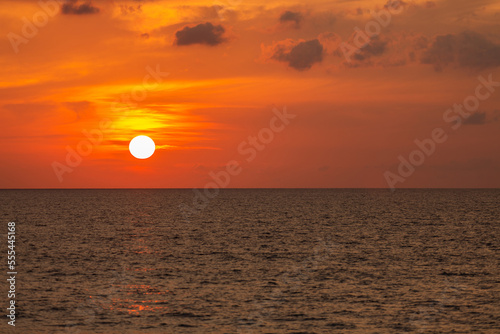 Fototapeta Naklejka Na Ścianę i Meble -  Image of a large sun on the beach with waves crashing Shining through the clouds, the golden sky looks so relaxing.