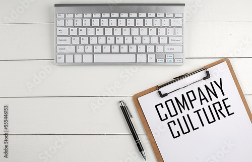 Home office workspace with keyboard, clipboard and pen with text COMPANY CULTURE on white wooden background , business concept