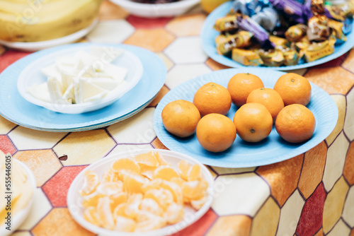 New Year's fruits on the table. Tangerines and sweets on an orange table lie on plate