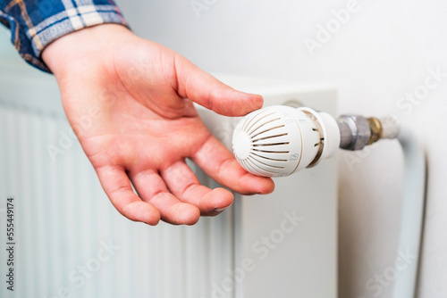 Hand on the faucet or temperature regulator on the radiator of the heating system, selective focus. Background