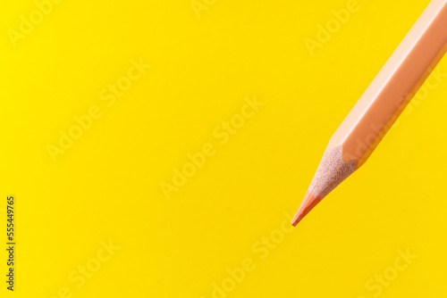 Colored pencil close-up with selective focus on the stylus and a blurred yellow background. Copy space