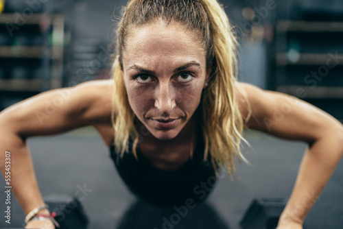 Close up photo of a woman doing push-ups using dumbbells