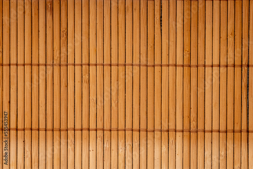 Brown bamboo texture background coming from natural bamboo straws. The oriental asian fencing has a beautiful yellow pattern, fence texture in daytime