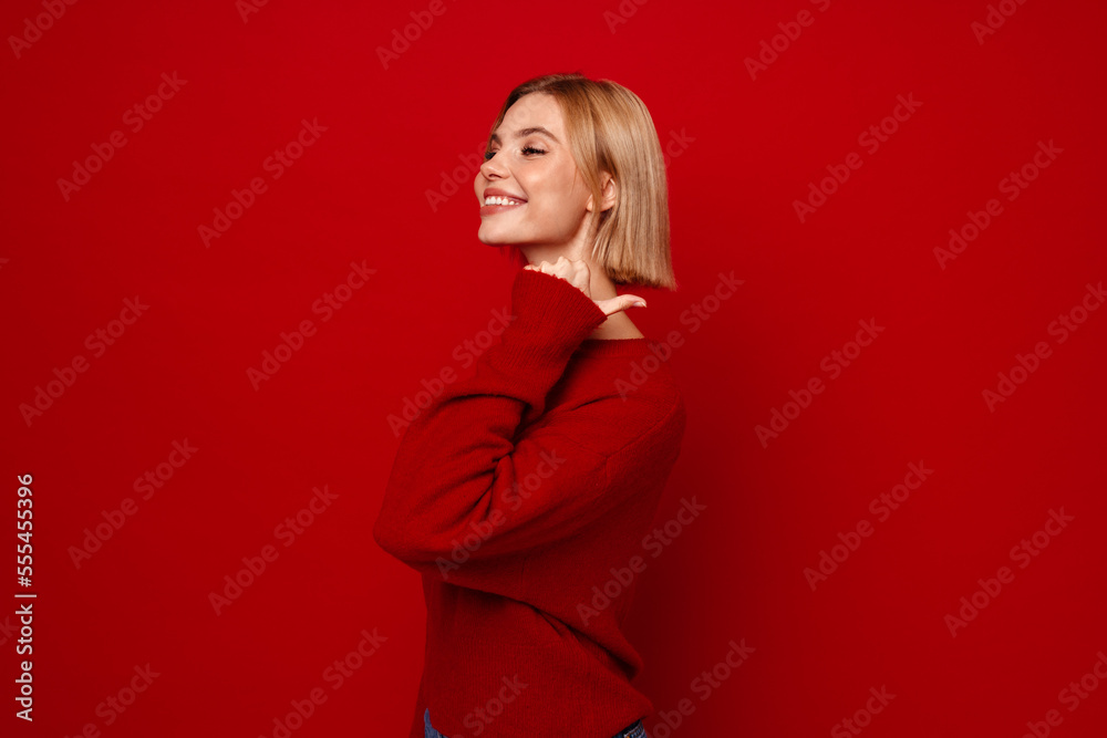 Smiling woman pointing finger at copy space isolated over red wall Smiling woman pointing finger at copy space isolated over red wall