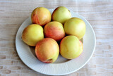 yellow plums on white plate on beige background isolated, close-up