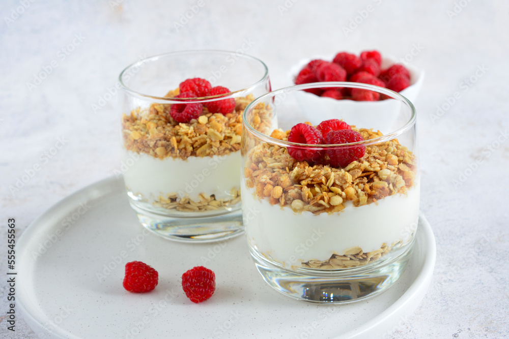 granola with greek yogurt and garden raspberry in drinking glasses on white background granola with greek yogurt and garden raspberry in drinking glasses on white background