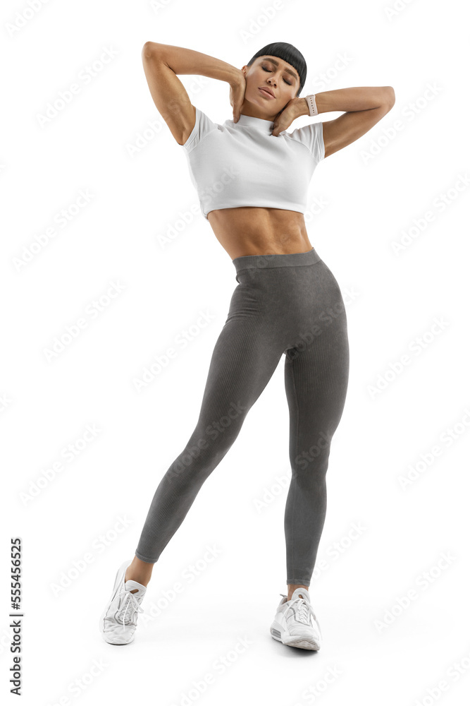Athletic muscular young girl enjoys her beautiful muscular slim body. The concept of a healthy lifestyle. Pleasure after sports work out, exercise. Blank sportswear, gray leggings and a white crop top