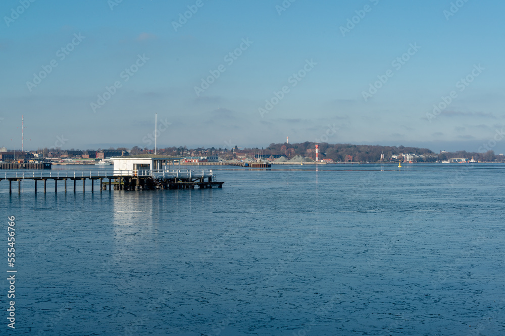 Gefrorenes Wasser in der Kieler Förde am Nordhafen im Vordergrund ein Bootshaus mit Steg