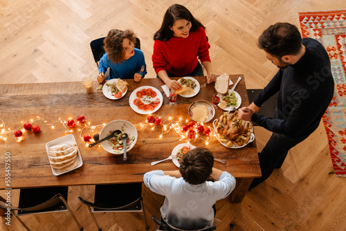 Big happy family having christmas dinner while sitting by table at home