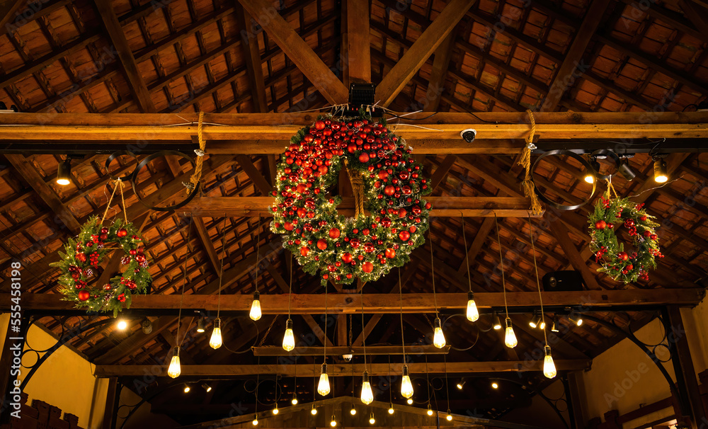 Obraz premium Close up of beautiful Christmas wreaths and balls. Bokeh garlands in the background. New Year and christmas concept with copy space, green tree, red berries