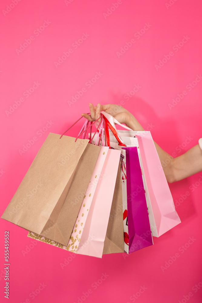 Female hand holding packages with on pink background Beauty Shopping Gifts Right hand Close up