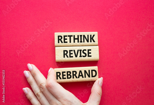 Rethink Revise Rebrand symbol. Wooden blocks with words Rethink Revise Rebrand. Beautiful red background. Businessman hand. Business and Rethink Revise Rebrand concept. Copy space. photo