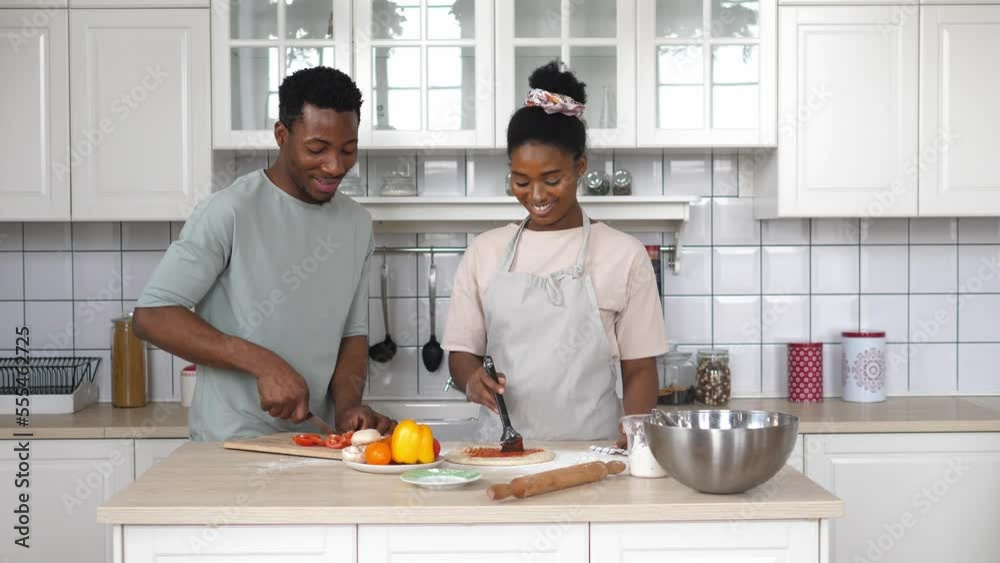 Happy young romantic couple of mixed race are cooking dinner together in the kitchen. Happy young romantic couple of mixed race are cooking dinner together in the kitchen.
