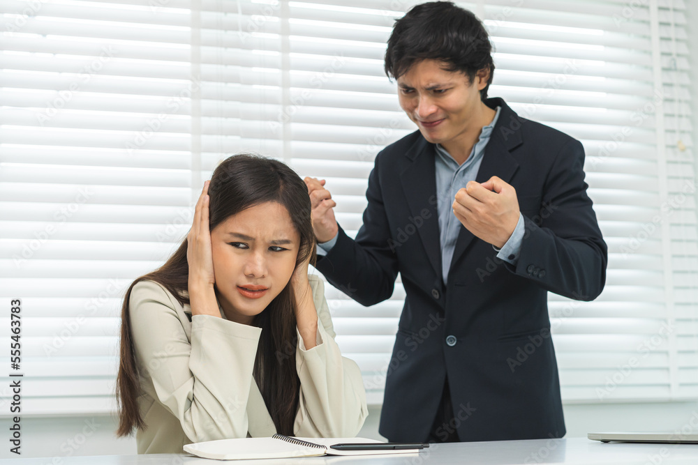 Angry boss, stressed asian young business, employee, secretary woman sitting at desk, hand cover her ears feel upset from annoying boss, colleague conflict with manager mistake about job at office. Angry boss, stressed asian young business, employee, secretary woman sitting at desk, hand cover her ears feel upset from annoying boss, colleague conflict with manager mistake about job at office.